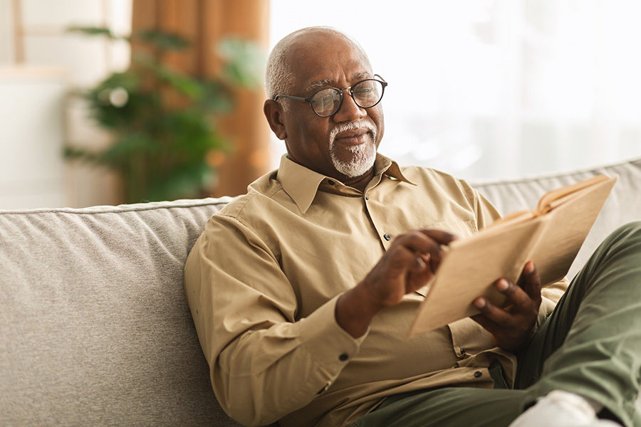 Senior sitting on a couch with a book.