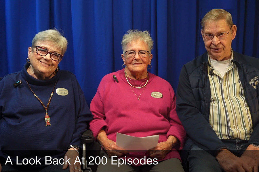 Three seniors sitting in front of a blue curtain.