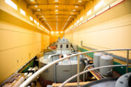 Large long room within the dam containing large encased turbines.